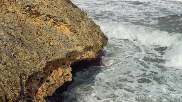 在一个阳光明媚的日子里，海浪拍打着岩石海岸，这是慢动作视频视频素材