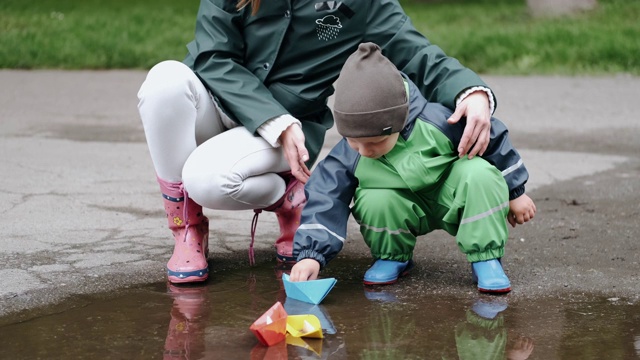 穿着雨靴在雨公园玩的有趣的孩子视频素材