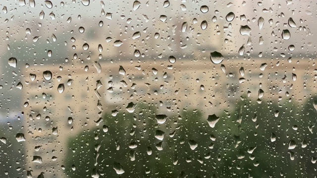 大雨。在刮风的雷雨中，雨滴从窗玻璃上滚下来。特写镜头，4K视频素材