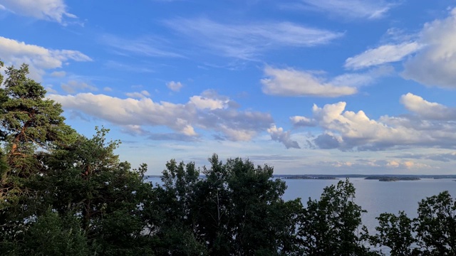 美丽的自然景观，观赏时间流逝与观赏波罗的海。在晴朗多风的夏夜，绿色的森林树木在蓝天和白云的背景上。视频素材