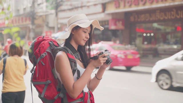 亚洲女摄影师，年龄20-30岁。“桥背包”旅游博主使用相机在泰国徒步拍摄在线旅游频道的视频片段。视频素材