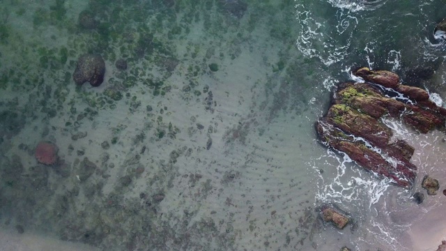 鸟瞰图的海浪打破在蓝色的海洋岩石。海浪对美丽的海滩鸟瞰图无人机4k拍摄。鸟瞰图的海浪撞击一个空的石头岩石悬崖从上面。视频素材