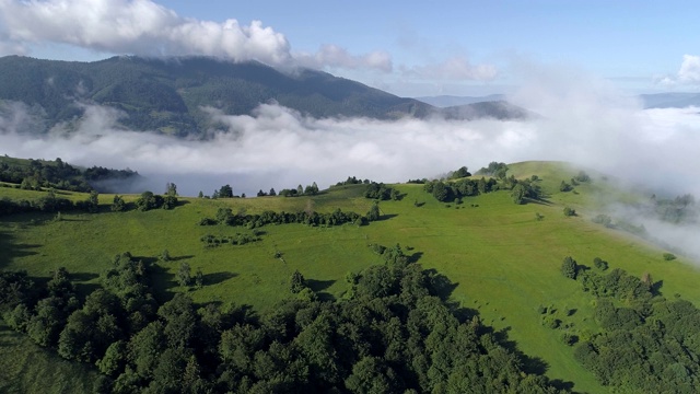 云雾缭绕的壮丽山景。山上长满了绿草和森林。飞行在雾中。空中射击,4 k视频素材