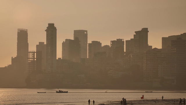 夕阳映衬在孟买的摩天大楼上。乔佩蒂海滩的景色视频素材