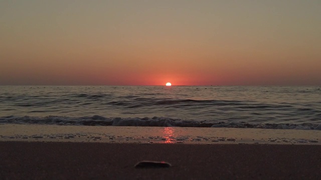 夕阳西下时，红色和橙色的太阳反射在水面上，海浪逼近。波慢动作视频素材