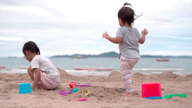 一个小女孩和她的小妹妹在沙滩上玩沙子视频素材