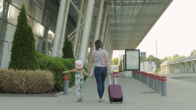 母亲和女儿步行去机场。拎着旅行袋的女人。孩子和妈妈的假期。后视频素材