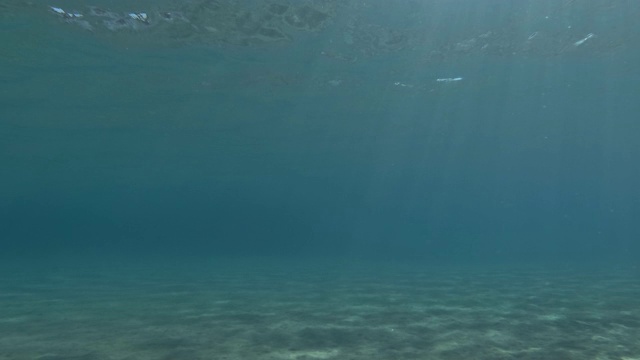 水面和耀眼的阳光照射在沙质海底。水下海景，海床上的阳光。地中海视频素材