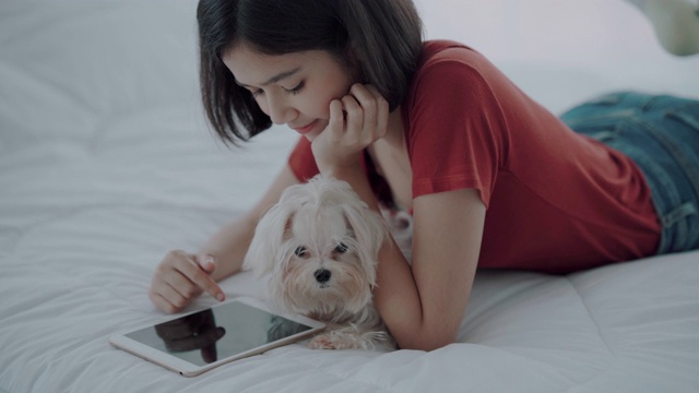 女孩和她的狗躺在卧室里视频素材