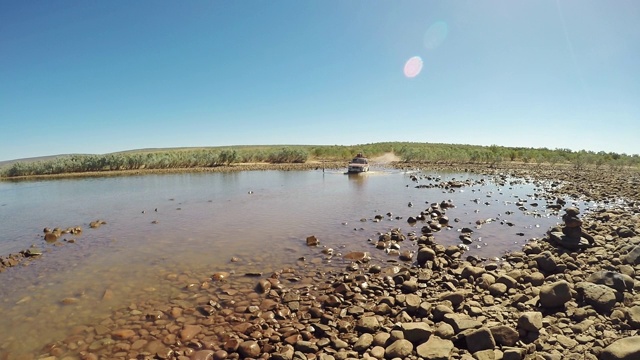 手持拍摄显示一个4x4驾驶通过五旬考斯特河渡口在旱季，吉布河路，金伯利，西澳大利亚，澳大利亚视频素材