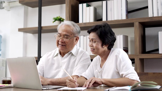 一对老年夫妇在用笔记本电脑理财视频素材