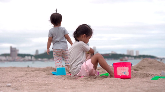 一个小女孩和她的小妹妹在沙滩上玩沙子视频素材