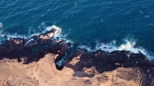 无人机沿着岩石海滩飞行。美丽的海岸线和海浪。大海岩石的鸟瞰图。顶视图的大浪打击海岸特内里费，加那利群岛，西班牙。高质量的4k镜头。视频素材