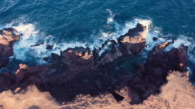 无人机沿着岩石海滩飞行。美丽的海岸线和海浪。大海岩石的鸟瞰图。顶视图的大浪打击海岸特内里费，加那利群岛，西班牙。高质量的4k镜头。视频素材