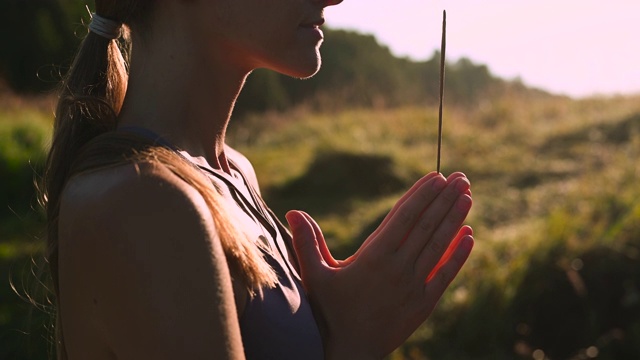 瑜伽女人穿着运动服冥想和呼吸在大自然的日出。烟从手中芳香的棍视频素材