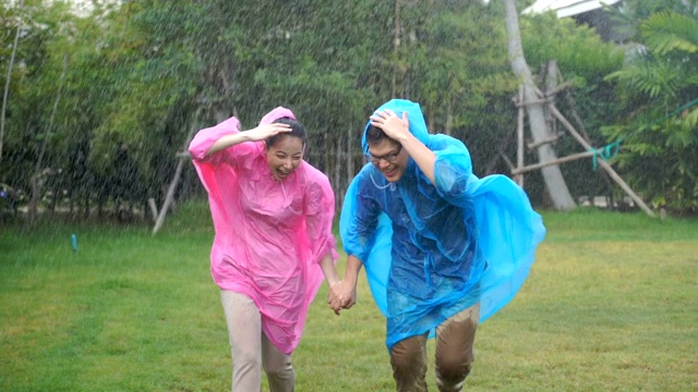 一对亚洲夫妇在倾盆大雨中奔跑视频素材