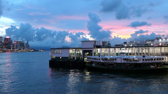 天星小轮穿过维多利亚港，从尖沙咀驶往香港岛，夕阳下的背景是香港标志性的天际线视频素材