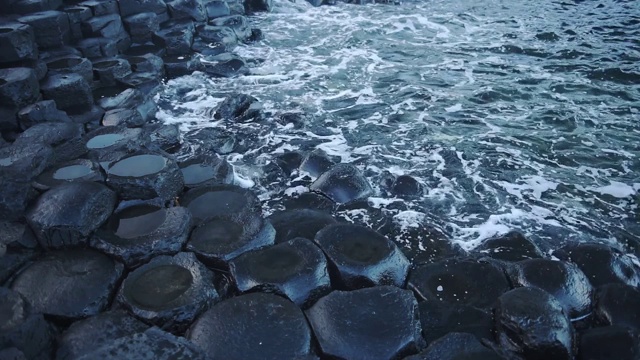 北爱尔兰安特里姆海岸，海浪冲击着巨人堤道的玄武岩岩层。——中景镜头视频素材