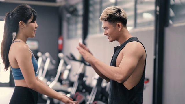 健康的两个人年轻的亚洲女人和男人在健身房做击掌手势后在健身房夫妇在一起，团队合作和伙伴健身的生活方式。视频素材