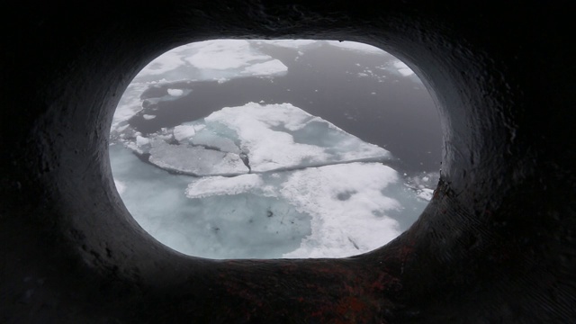 在斯瓦尔巴特群岛北海岸，一艘用冰加固的船在北纬80度的海面上冲破腐烂的海冰。视频素材