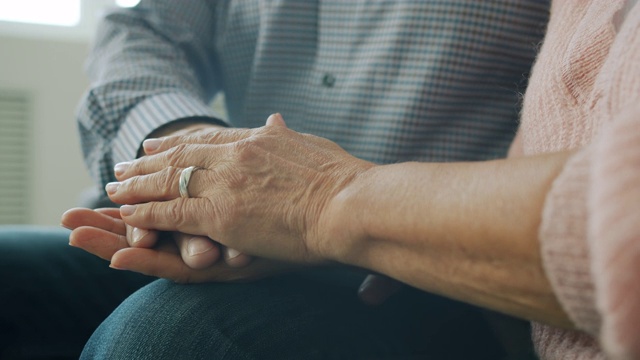 特写的老男人和女人的手在室内表达爱和照顾视频素材