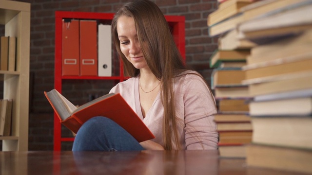 年轻女学生阅读纸书。女学生与一本书的教育。女人学习。回家学习。远程教育。聪明的聪明的女人。自我教学。大学的知识。文学。视频素材