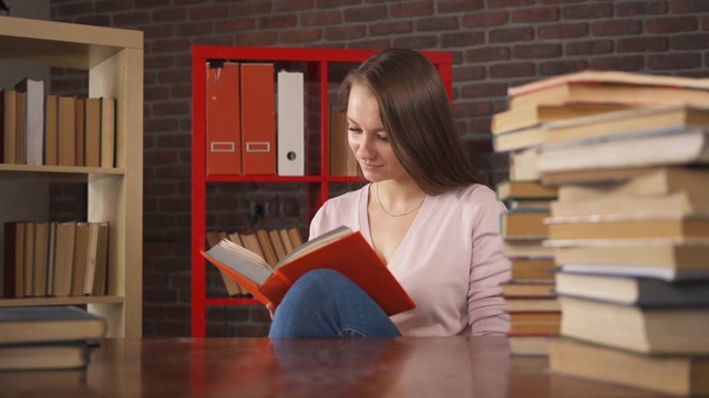 年轻女学生阅读纸书。女学生与一本书的教育。女人学习。回家学习。远程教育。聪明的聪明的女人。自我教学。大学的知识。文学。视频素材