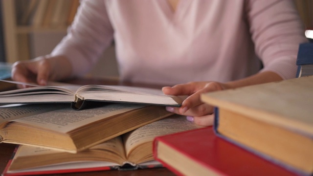 年轻女学生在接受教育时翻开纸书。女学生正坐在大学图书馆的桌子旁看书。女人学习。回家学习。聪明的聪明的女人。视频素材