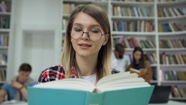 相当冷静专注的年轻女子戴着眼镜在大学图书馆看书视频素材