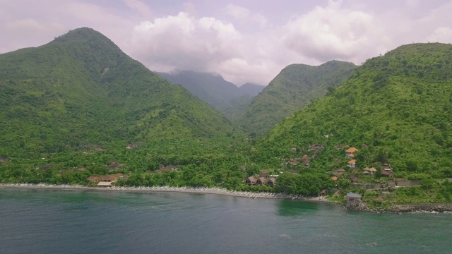 在宁静的海滩附近郁郁葱葱的绿色山脉上的热带度假胜地的豪华景色视频素材