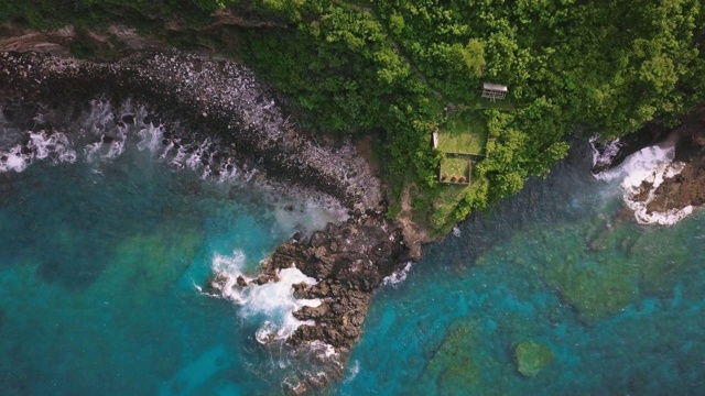 空中俯瞰岩石嶙峋的海岸线，绿色的悬崖和蓝色的大海视频素材