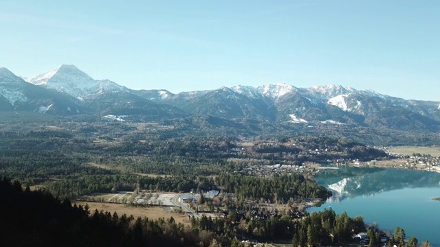 一对在奥地利欣赏Faaker See的夫妇。周围有高山山脉，反射在清澈平静的湖面上。小村庄围绕着湖。白雪皑皑的山脉视频素材