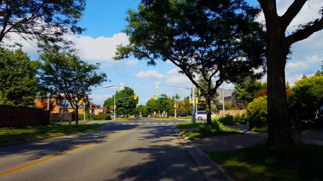 等待红灯的车辆。在城市郊区的交通灯十字路口，夏天的交通灯变绿，车辆左转。汽车在城市郊区的交通灯十字路口等待绿灯在白天。视频素材