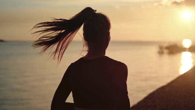 运动女性与波浪的头发运行在海滩在戏剧性的太阳。红色摄像机中拍摄视频素材