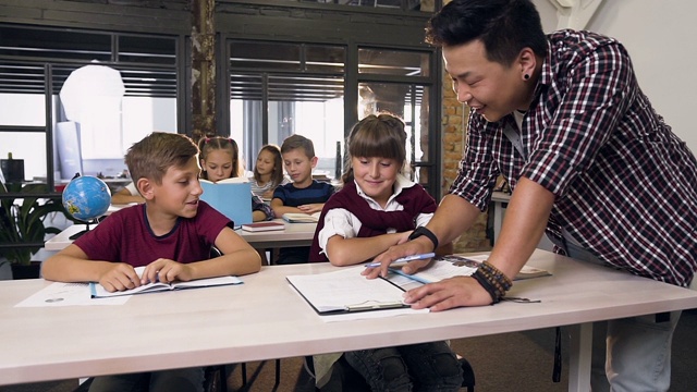 年轻的韩国男教师帮助小学生在课堂上学习视频素材