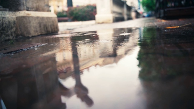 一个欧洲城市的背景上的水坑和雨滴的圆圈视频素材