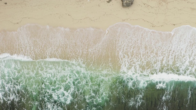 鸟瞰海浪撞击空沙滩。视频下载