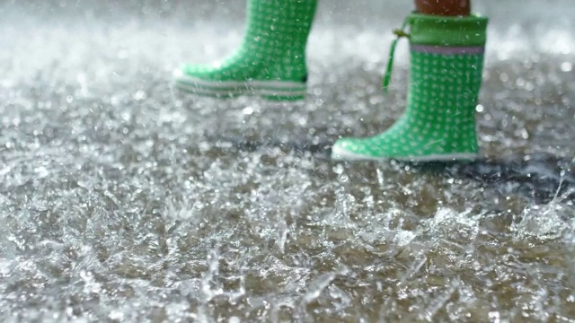 孩子们穿着胶靴在大雨中行走视频素材