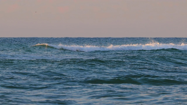 浮标漂浮在海面上。日出的海浪向海滩滚滚而来视频素材