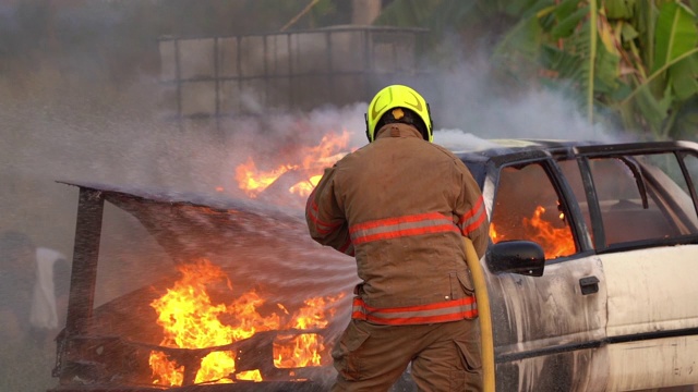 在一场车祸中，消防员用慢镜头向燃烧着的大火喷水视频素材