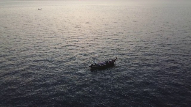 航拍泰国安达曼海上的一艘长尾出租车船。夕阳在地平线上闪烁着金色和橙色的光芒视频下载