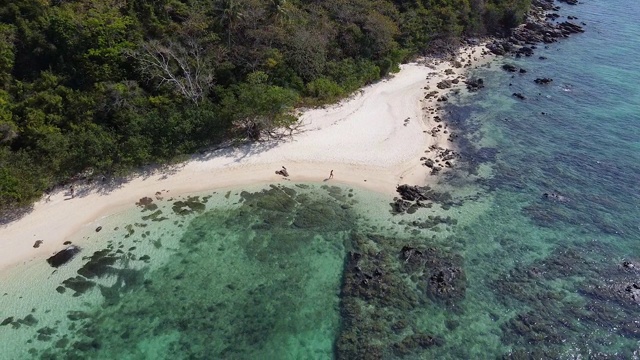 鸟瞰整个热带亚洲小岛，游客在安达曼海的蓝色清澈的海水中沿着珊瑚礁附近的白色沙滩散步，泰国普吉岛。视频下载