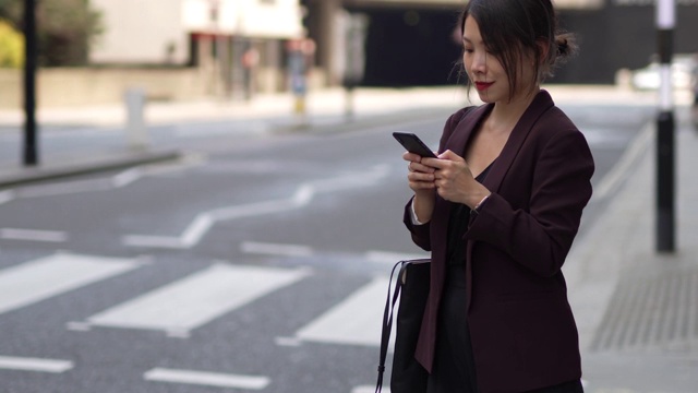 年轻的亚洲女商人在城市为她的车叫手机在她的手视频素材