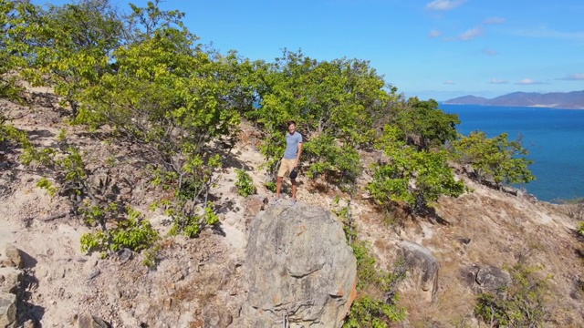 航拍的一个年轻人坐在山上的一块岩石上。徒步旅行的概念视频素材