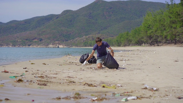 戴手套的人在海滩上收集塑料垃圾。沙滩上的垃圾问题是由人为污染造成的。环保运动，清洁环境。生态志愿服务概念视频素材