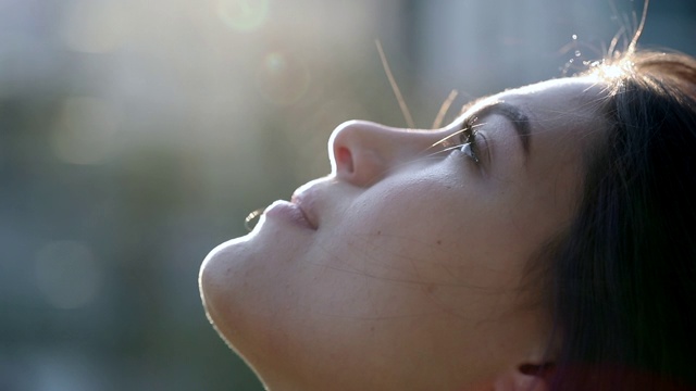 沉思的年轻女子带着信念和希望仰望天空。忠实的女孩侧面脸与镜头眩光外面视频素材