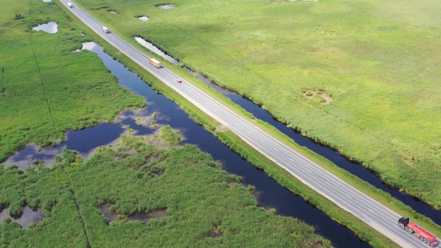 鸟瞰图的快速卡车在乡村和沼泽地形的道路上视频下载