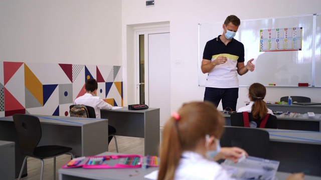 戴口罩的年轻男教师在疫情期间激励孩子学习视频素材