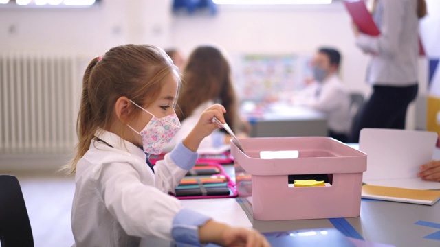 可爱的小学小女孩戴着面具在教室里视频素材