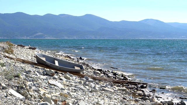 灰色的小船停在海边的石滩上视频素材